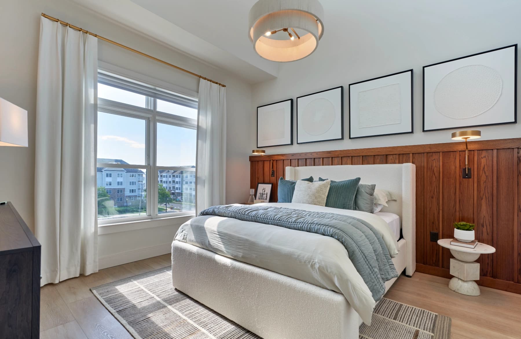 Liora residence bedroom with wood accent wall and large window