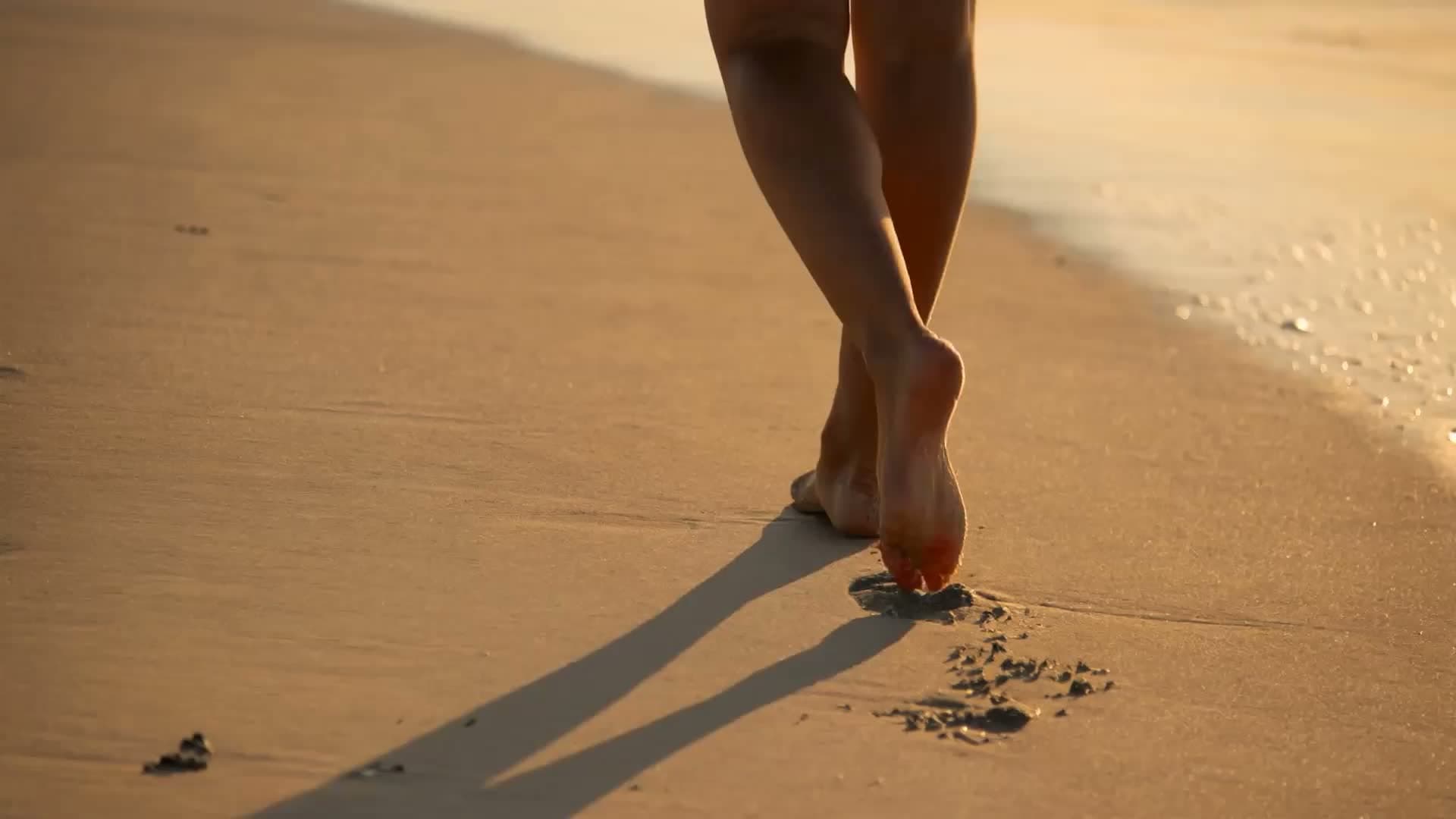 Person walking barefoot along the beach at sunset | Offsite Photography
